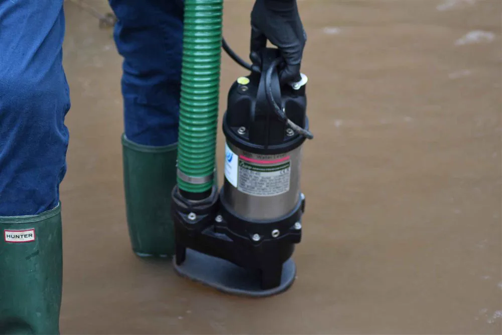 Simon Crowther carrying a pump through flood water