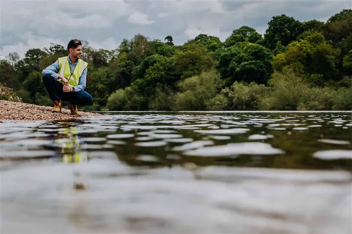 Simon Crowther inspecting a river from a shingle bank during a site investigation