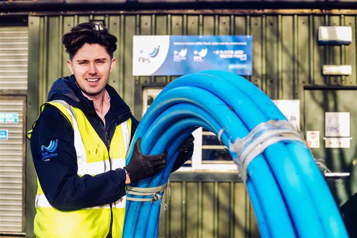 Simon Crowther with coiled blue water pipe at the Flood and Water Pumps depot