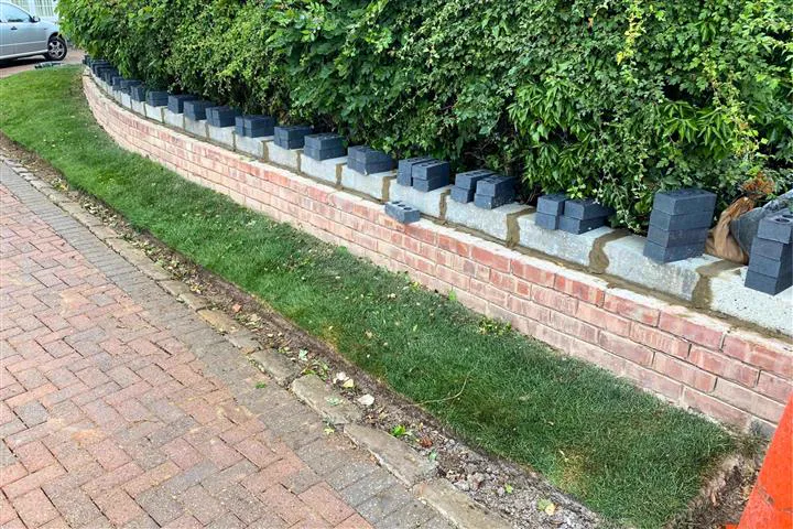 A low brick flood wall under repair with engineering bricks being laid