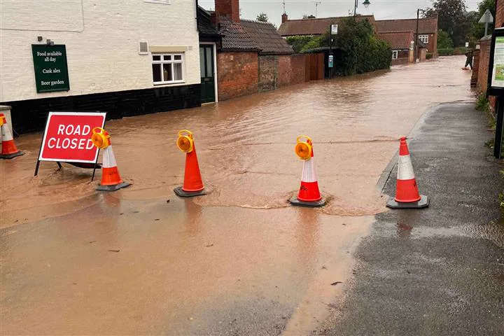 A flooded village street closed to traffic during a flood