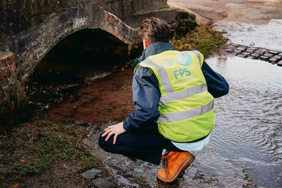 Simon Crowther inspecting a culvert beneath a brick road bridge