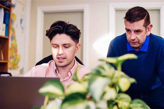 Simon Crowther reviewing information on a laptop with a colleague